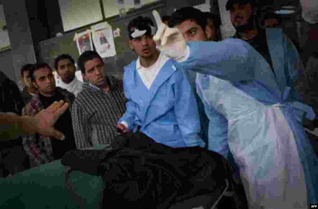 Hospital staff at the Jalaa hospital react after a body was brought into the hospital in Benghazi, eastern Libya, Saturday, March 19, 2011. Explosions shook the Libyan city of Benghazi on Saturday while a fighter jet was heard flying overhead, and residen