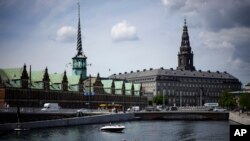 ARCHIVO - Un barco navega por el río Nyhavn, con el edificio de la Antigua Bolsa de Valores al fondo, en Copenhague, Dinamarca, el 29 de junio de 2022.