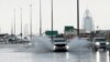 An SUV splashes through standing water on a road with the Burj Al Arab luxury hotel seen in the background in Dubai, United Arab Emirates, April 16, 2024.