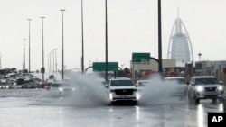 An SUV splashes through standing water on a road with the Burj Al Arab luxury hotel seen in the background in Dubai, United Arab Emirates, April 16, 2024.