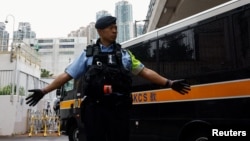 (FILE) A police officer stands guard as a prison van arrives at the West Kowloon Magistrates' Courts building, in Hong Kong, China November 19, 2024.