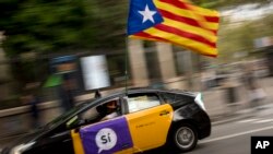 Seorang pria mengendarai taksinya yang dihiasi bendera estela dan berbagai atribut yang mendukung pemilihan 1 Oktober di Barcelona, Spanyol, Jumat 22 September 2017. (AP Photo/Emilio Morenatti)