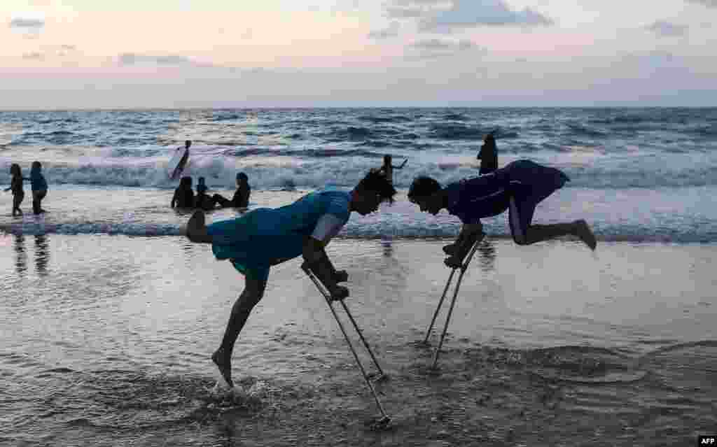 Palestinian amputees Mohammed Eliwa, 17, and Ahmed al-Khoudari (R), 20, who each lost a leg during clashes on the border with Israel, play on the beach in Gaza City, Aug. 20, 2019.