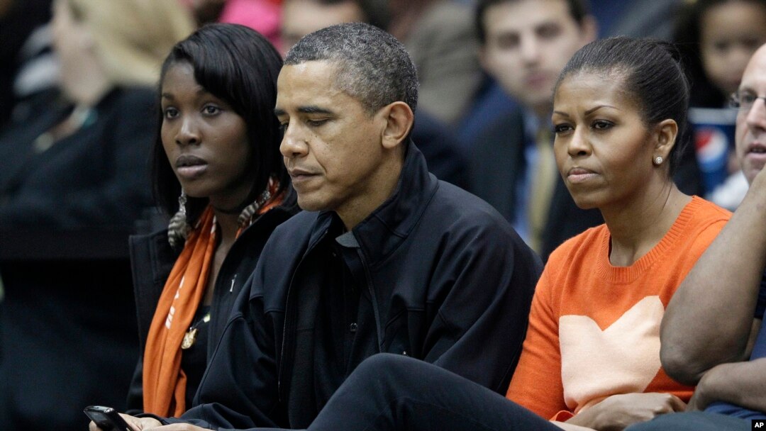Presiden Barack Obama, di samping ibu negara Michelle Obama, mengecek BlackBerrynya ketika menonton pertandingan bola basket di Towson, Maryland, 26 November 2011. (Foto: dok.)