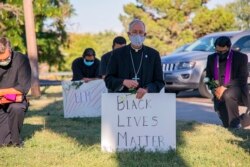 Uskup El Paso Mark Seitz (tengah) berlutut bersama para demonstran di Memorial Park sambil memegang poster Black Lives Matter di El Paso, Texas, 1 Juni 2020. (Foto: AP)