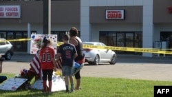 Zach, Zoe dan Melissa Cates meletakkan bunga dekat lokasi penembakan di Pusat Perekrutan Angkatan Bersenjata di Chattanooga, Tennessee (16/7).