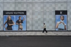 FILE - A man wearing a face mask walks past a store of French luxury brand Louis Vuitton at a shopping mall in Wuhan, the epicenter of the novel coronavirus outbreak, Hubei province, China, February 25, 2020.