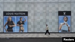 A man wearing a face mask walks past a store of French luxury brand Louis Vuitton at a shopping mall in Wuhan, the epicentre of the novel coronavirus outbreak, Hubei province, China, Feb. 25, 2020.