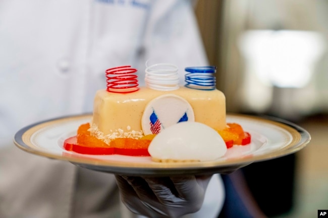 White House executive pastry chef Susie Morrison, right, holds a dish during a media preview for the State Dinner with President Joe Biden and French President Emmanuel Macron in the State Dining Room of the White House in Washington, Wednesday, Nov. 30, 2022. The dinner will include a butter poached Maine lobster, beef with shallot marmalade, American artisanal cheeses, and an orange chiffon cake for desert. (AP Photo/Andrew Harnik)