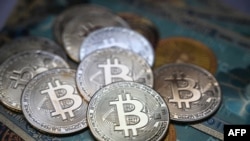 Foto ilustrasi yang diambil pada 19 Juli 2021 di Istanbul ini menunjukkan uang kertas fisik dan koin tiruan dari mata uang kripto Bitcoin. (Foto: AFP/Ozan Kose)