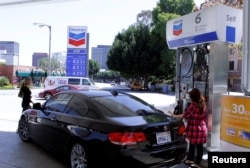 FILE - A woman stands at a gas pump at a Chevron gasoline station in Los Angeles, California April 11, 2011. In Britain, it is called a petrol station. (REUTERS/Fred Prouser/File Photo)