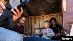An asylum-seeking migrant family from Brazil rest in a handmade shack while waiting to be transported by the U.S. Border Patrol after crossing the border from Mexico into the United States in Jacumba Hot Springs, California, April 29, 2024.