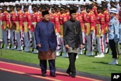 Presiden Prabowo Subianto, kiri, dan pendahulunya Joko Widodo memeriksa pengawal kehormatan saat upacara serah terima mereka di Istana Merdeka, Jakarta, 20 Oktober 2024. (AP Photo/Achmad Ibrahim)