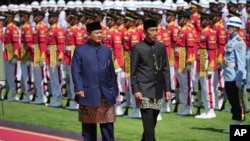 Presiden Prabowo Subianto dan mantan Presiden Joko Widodo (kiri) memeriksa pasukan kehormatan, dalam acara serah-terima jabatan di Istana Merdeka, Jakarta, Minggu, 20 Oktober 2024. (Foto: Achmad Ibrahim/AP Photo)