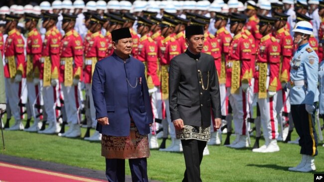 Presiden Prabowo Subianto dan mantan Presiden Joko Widodo (kiri) memeriksa pasukan kehormatan, dalam acara serah-terima jabatan di Istana Merdeka, Jakarta, Minggu, 20 Oktober 2024. (Foto: Achmad Ibrahim/AP Photo)