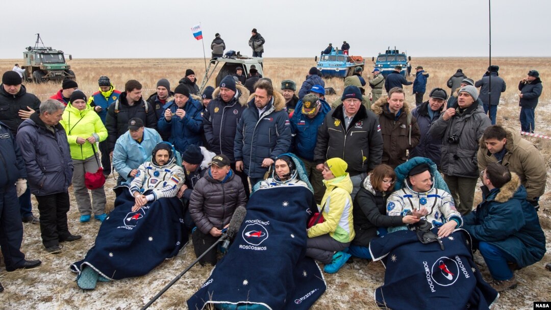 FILE - Russian cosmonauts Mikhail Kornienko, left, Sergey Volkov of Roscosmos, center, and Expedition 46 Commander Scott Kelly of NASA, rest in chairs outside of the Soyuz TMA-18M spacecraft just minutes after they landed in a remote area near the town of Zhezka