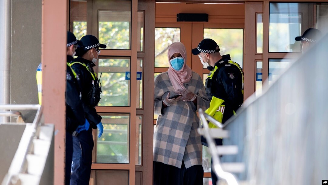 Police talk to a woman at housing commission apartments under lockdown in Melbourne, Australia, on Monday, July 6, 2020. The leader of Australia’s most populous state says her government’s decision to close its border with hard-hit Victoria state…