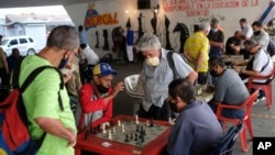 Men wearing masks play chess under a bridge in Caracas, Venezuela, Saturday, Dec. 26, 2020, amid the new coronavirus pandemic. (AP Photo/Matias Delacroix)