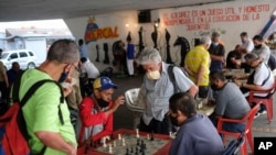 Men wearing masks play chess under a bridge in Caracas, Venezuela, Dec. 26, 2020, amid the new coronavirus pandemic. 