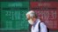 A man walks past an electronic stock board showing Japan's Nikkei 225 index and New York Dow Jones index at a securities firm in Tokyo, June 15, 2020. 