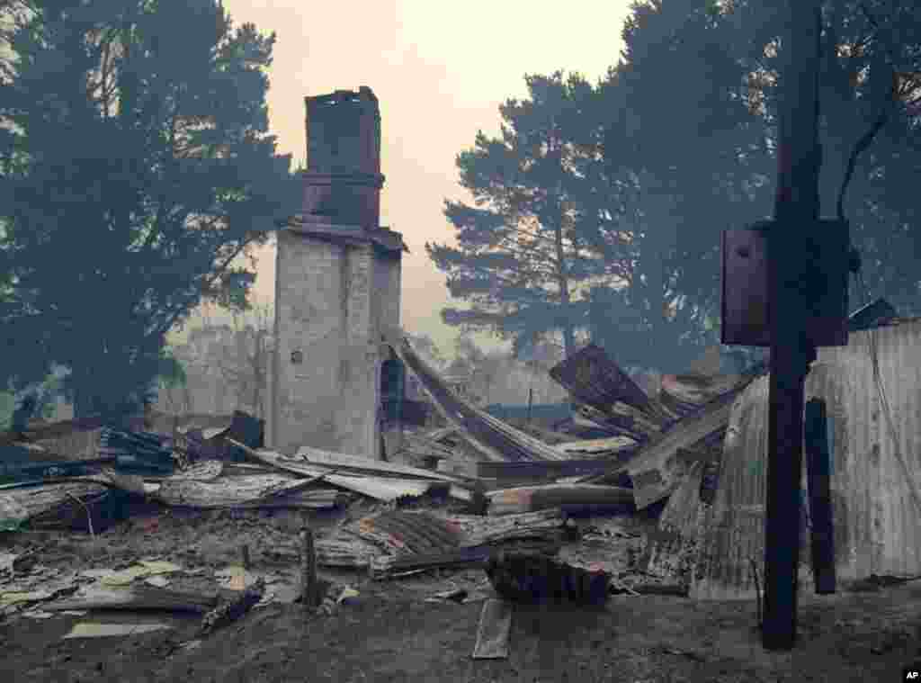 In this photo provided by the New South Wales Rural Fire Service, the remains of a structure are in a crumpled pile after a wildfire destroyed the building, at an unknown location in Australia, Oct. 17, 2013. 