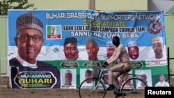 FOTO ARSIP: Seorang pengendara sepeda melintasi poster kampanye Presiden Muhammadu Buhari di sebuah jalan setelah tertundanya pilpres. Kano, Nigeria, 17 Februari 2019 (foto: Reuters/Luc Gnago/Foto Arsip)