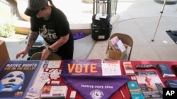 ARCHIVO - Shelby Davin, coordinadora de eventos y divulgación en el Phoenix Indian Center, organiza información para los votantes durante un evento del Día de los Pueblos Indígenas, el 14 de octubre de 2024, en Phoenix, Arizona. 