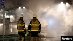 Firefighters keep an eye on several cars that were set on fire during a riot, according to local media, in Rinkeby suburb, outside Stockholm, Sweden, Feb. 21, 2017. 