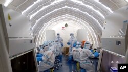 In this photo released by Xinhua News Agency and taken on June 23, 2020, staff members work in an inflatable COVID-19 testing lab in Beijing.