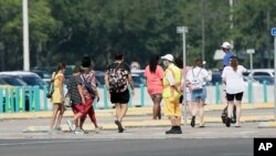 Un empleado da instrucciones a las personas en la entrada del parque de diversiones Magic Kindgom, en la reapertura de Walt Disney World, en Florida, el sábado 11 de julio de 2020.