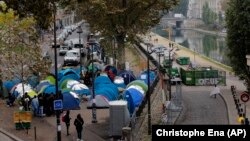 Migrants stand in a makeshift camp in Paris, France, Friday, Oct. 28, 2016. 