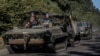 Ukrainian servicemen ride an armoured personnel carrier near the Russian border in Sumy region