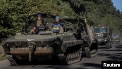 Ukrainian servicemen ride an armoured personnel carrier near the Russian border in Sumy region