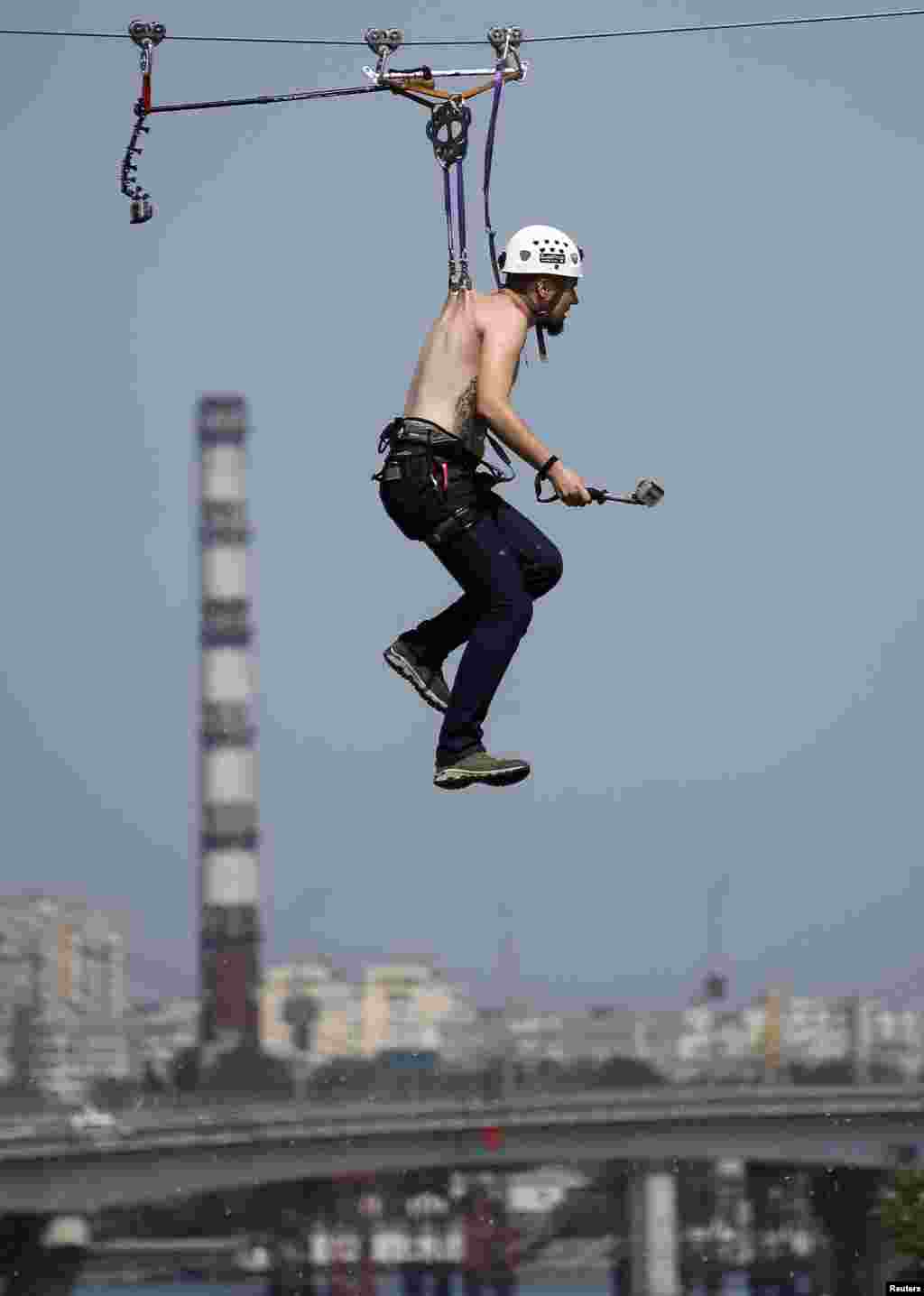 Pavlo Klets, 24, rides a Tyrolean traverse over the Dnipro River, suspended by a cable wire with metal clamps pierced directly into the skin of his back to set a national record for the longest distance travelled on a Tyrolean traverse