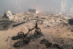 A charred tricycle is left behind in a fire-ravaged home after the CZU August Lightning Complex Fire in Bonny Doon, Calif., Aug. 20, 2020.