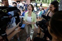 Democratic presidential candidate Sen. Amy Klobuchar, D-Minn., center, laughs while speaking with reporters, Aug. 18, 2019, at the Hillsborough County Democrats Summer Picnic, in Greenfield, N.H.