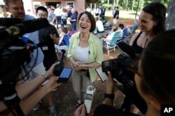 Democratic presidential candidate Sen. Amy Klobuchar, D-Minn., center, laughs while speaking with reporters, Aug. 18, 2019, at the Hillsborough County Democrats Summer Picnic, in Greenfield, N.H.
