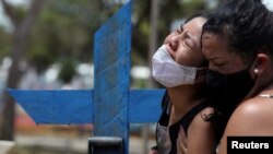 Kelvia, 16 ans, et sa tante, en pleurs lors de l'enterrement de sa mère Andrea dos Reis Brasao, décédée à 39 ans des suites de la maladie à coronavirus, Manaus, Brésil, 17 janvier 2021. (Reuters/Bruno Kelly)