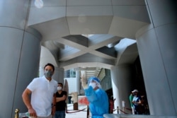 A staff member in a protective suit directs a HSBC staff to a temporary testing center for COVID-19 near the entrance to the HSBC headquarters in Hong Kong, March 17, 2021.