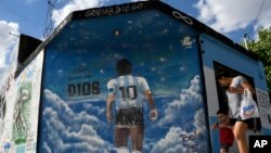 Des piétons passent devant une peinture murale représentant la légende du football décédé Diego Maradona dans le quartier de Lomas de Marilo, Buenos Aires, Argentine, le 22 novembre 2021.