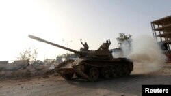 Fighters from the Benghazi Shura Council, which includes former rebels and militants from al-Qaida-linked Ansar al-Sharia, gesture on top of a tank next to the camp of the special forces in Benghazi, Libya, July 30, 2014. 