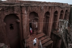 FILE - Ethiopian Orthodox devotees walk between the rock-hewn churches of Saint Gabriel and Saint Raphael in Lalibela, Ethiopia, March 7, 2019. Rebels from Ethiopia's war-hit region of Tigray swept into Lalibela on August 5, 2021.