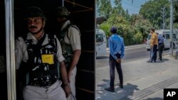 Indian paramilitary soldiers and policemen guard from behind a temporary security post as delegates from the Group of 20 nations arrive to participate in a tourism meeting in Srinagar, Indian controlled Kashmir, May 22, 2023. 