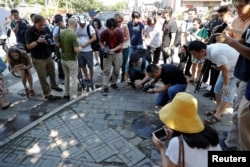 Reporters take pictures at the site of a blast outside the U.S. embassy in Beijing, China, July 26, 2018.