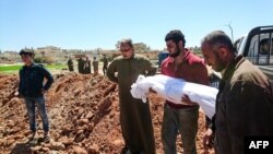 FILE - Syrians bury the bodies of victims of a a suspected toxic gas attack in Khan Sheikhun, a nearby rebel-held town in Syria’s northwestern Idlib province, April 5, 2017.