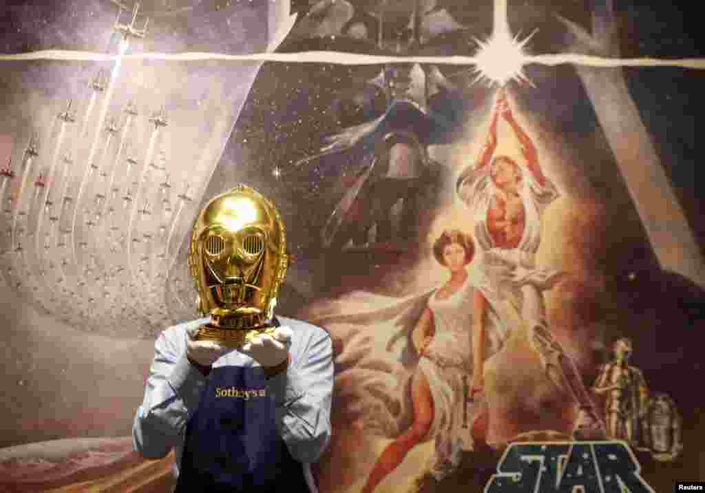 A Sotheby&#39;s employee poses with a &quot;Return of the Jedi&quot; promotional C-3PO Helmet 1983, estimated at &#163;15,000-&#163;25,000 created by George Lucas&#39; visual effects company, during a photocall at Sotheby&#39;s in London, Britain.