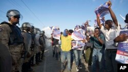 Demonstrators show pictures of ousted president Jean Bertrand-Aristide with former presidential candidate Maryse Narcisse during a march in favor of Senate President Jocelerme Privert for interim president, outside Parliament in Port-au-Prince, Haiti, Feb. 13, 2016.