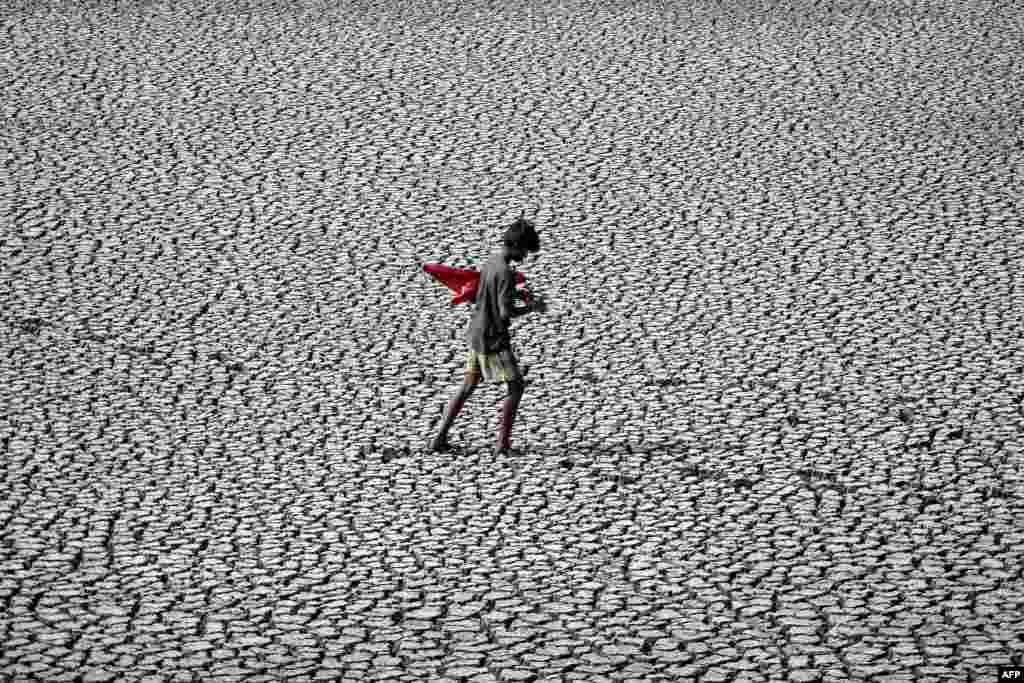 A youth walks on the parched bed of a temple tank during a hot day in Chennai, India.