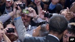 Members of the audience take photographs as President Barack Obama shakes hands at The National Association of Latino Elected and Appointed Officials’ Annual Conference at the Walt Disney World Resort in Florida, June 22, 2012.