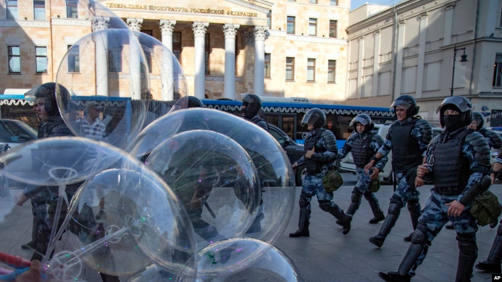 ARCHIVO - Policías pasan junto a un vendedor de globos mientras controlan una calle durante una protesta no autorizada ante el edificio de la Fiscalía General Rusa en Moscú, el sábado 27 de julio de 2019.